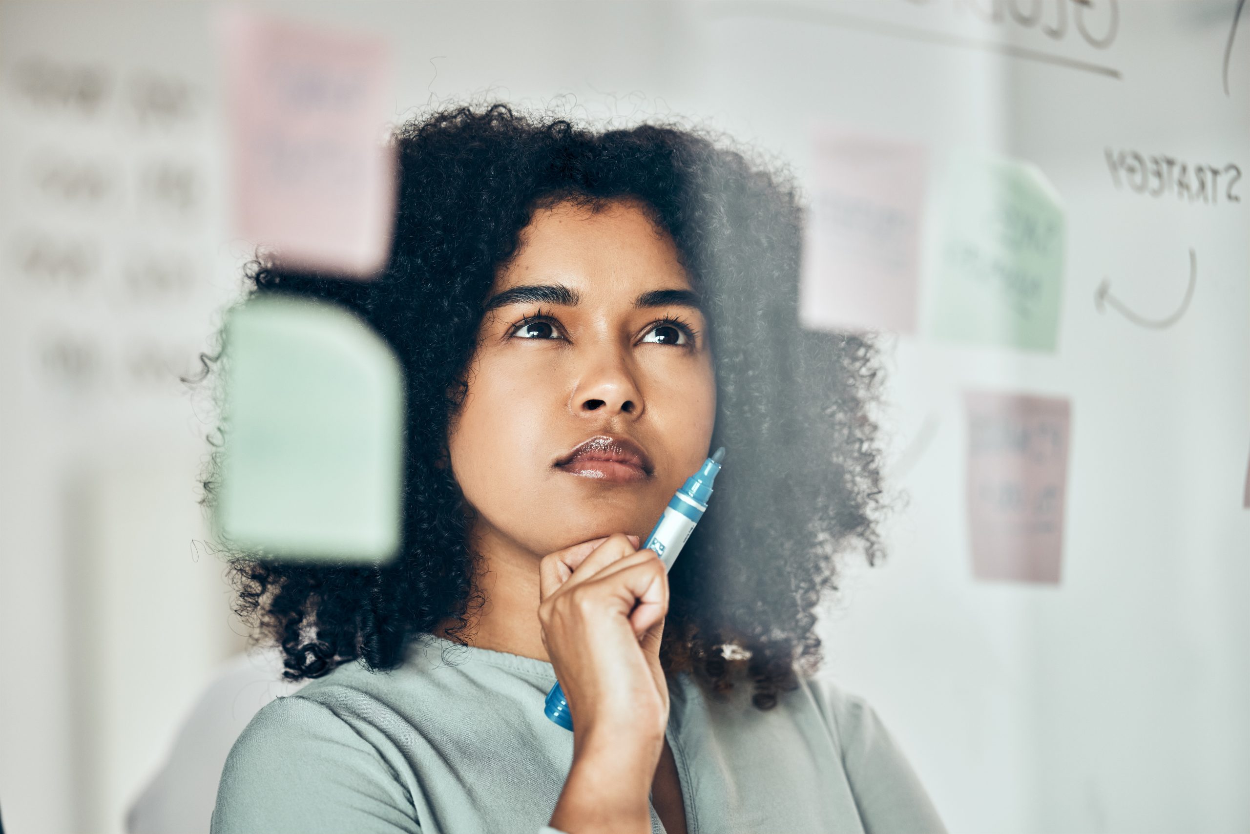 Mujer pelo negro pensando en pizarra estrategia de marketing digital